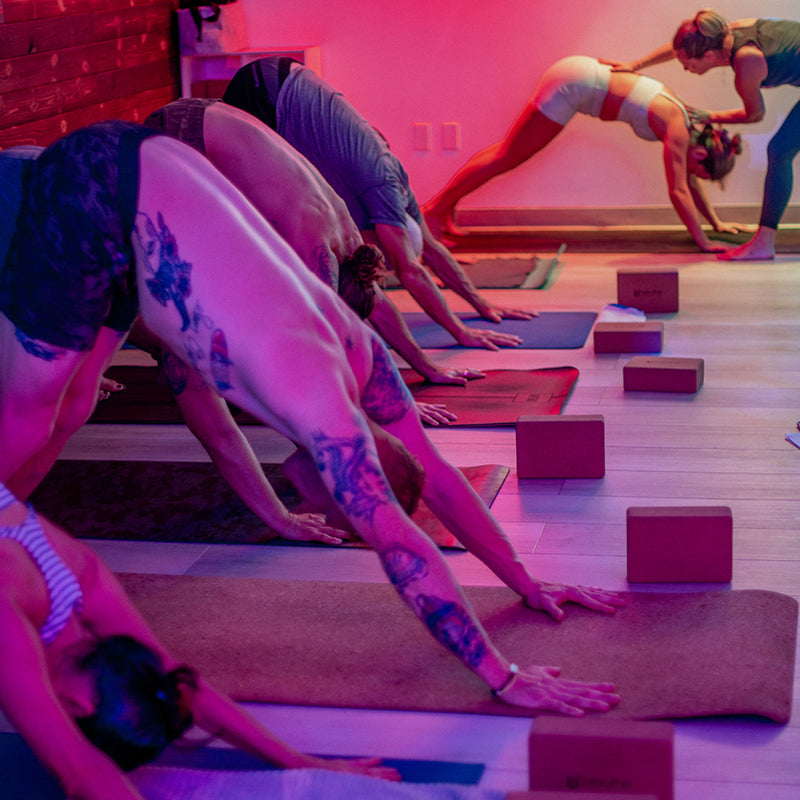 Image of a group taking a yoga class at breathe degrees with an instructor helping